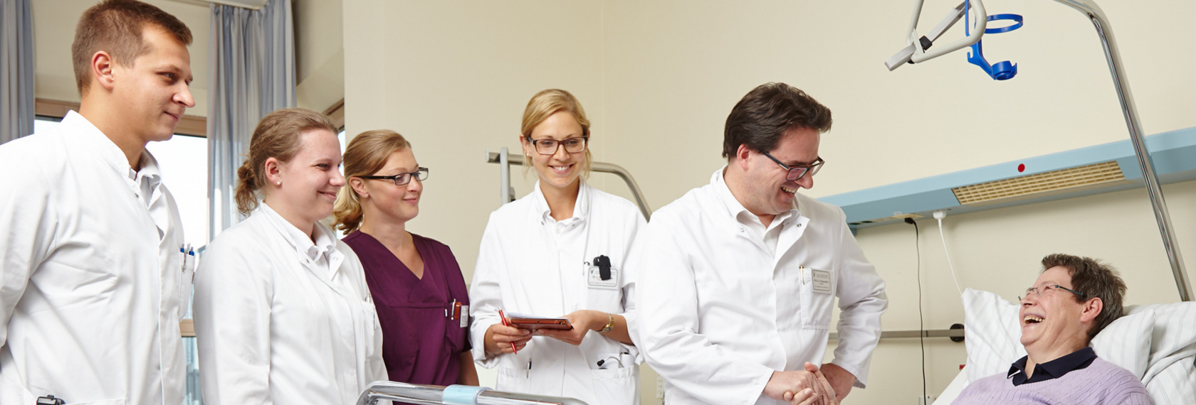 Ein Team aus Ärzten und Pflegepersonal führt die Visite in einem Patientenzimmer durch