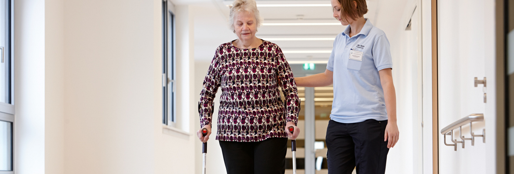 Eine Patientin übt das Gehen durch Unterstützung einer Physiotherapeutin