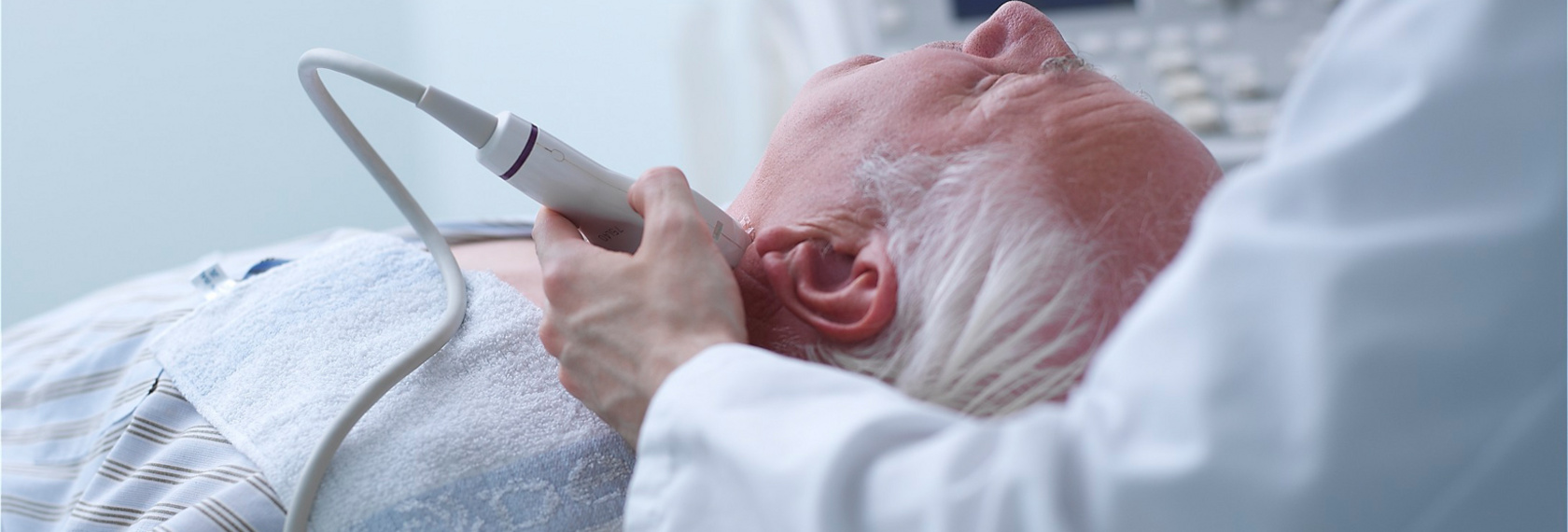 Arzt führt eine Untersuchung mittels Ultraschall an der Halsschlagader durch